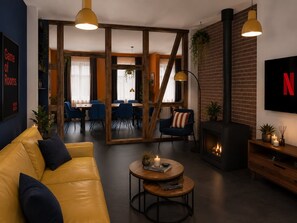 A modern living room with a sofa, a coffee table, a fireplace, and a TV mounted on the wall.