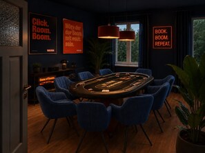 A room with a blackjack table, blue chairs, and neon signs.