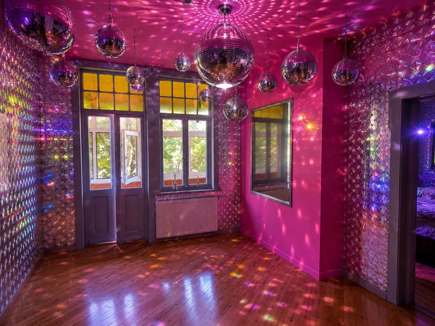 A room with wooden flooring, large windows, and disco balls.