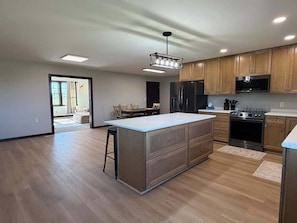 A modern kitchen with wooden cabinets, stainless steel appliances, and a central island.