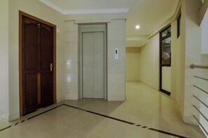 A hallway with a wooden door labeled '4C', a white elevator, and a glass door with a metal handle. - Collection O Kadavanthra Near South (Kanayannur)