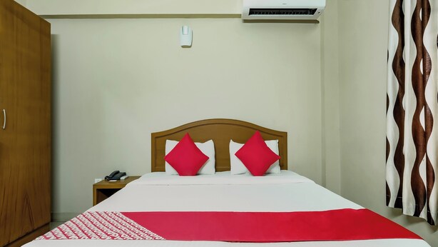Una habitación de hotel con cama, mesita de noche, teléfono y aire acondicionado.