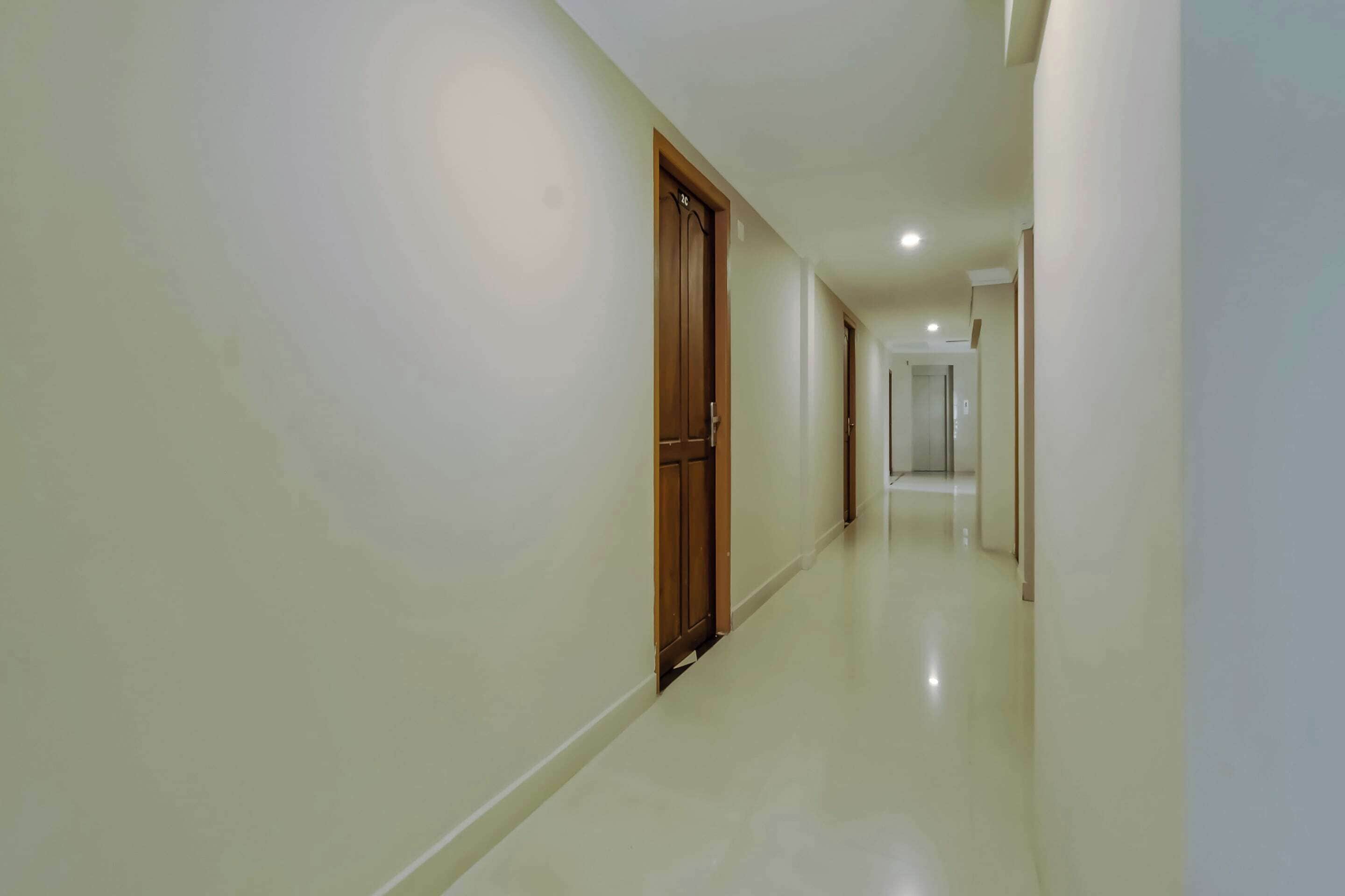 A corridor with a wooden door and a white wall.