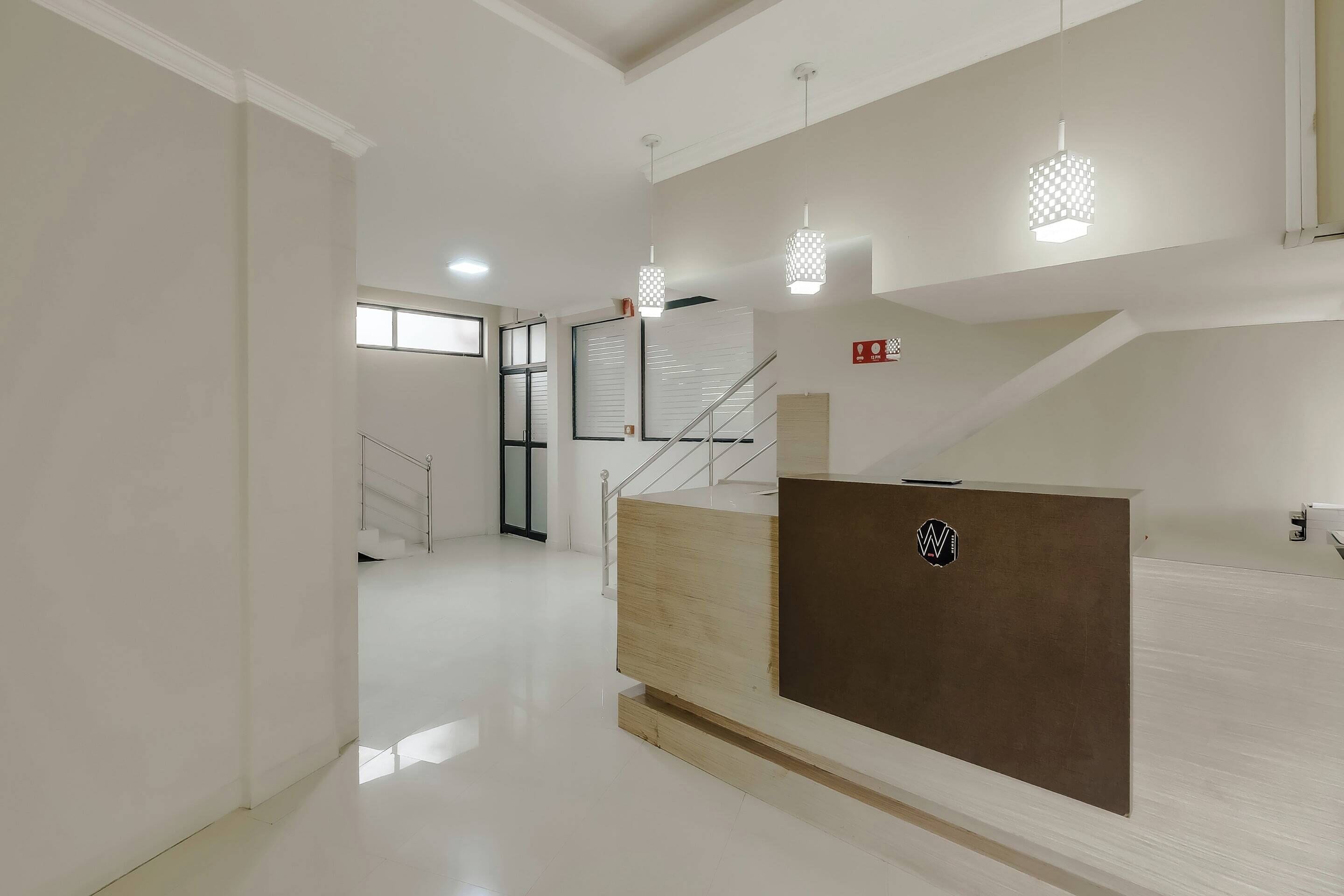 A modern interior with a reception desk, a staircase, and pendant lighting.
