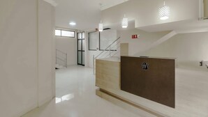 Un interior moderno con mostrador de recepción, escalera e iluminación colgante.