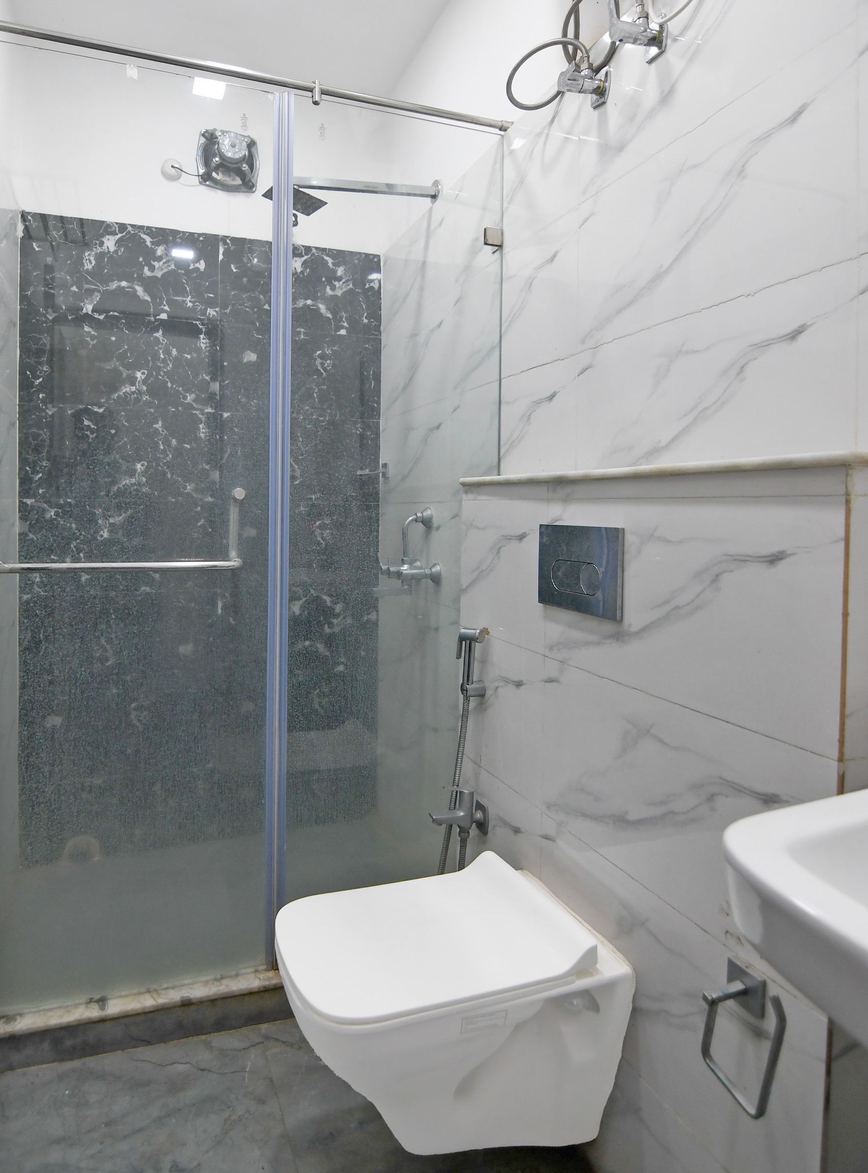 A bathroom with a glass-enclosed shower, a toilet, and a sink.