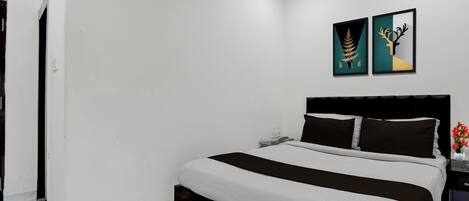 Habitación de hotel con cama, mesita de noche, teléfono y dos obras de arte en la pared.