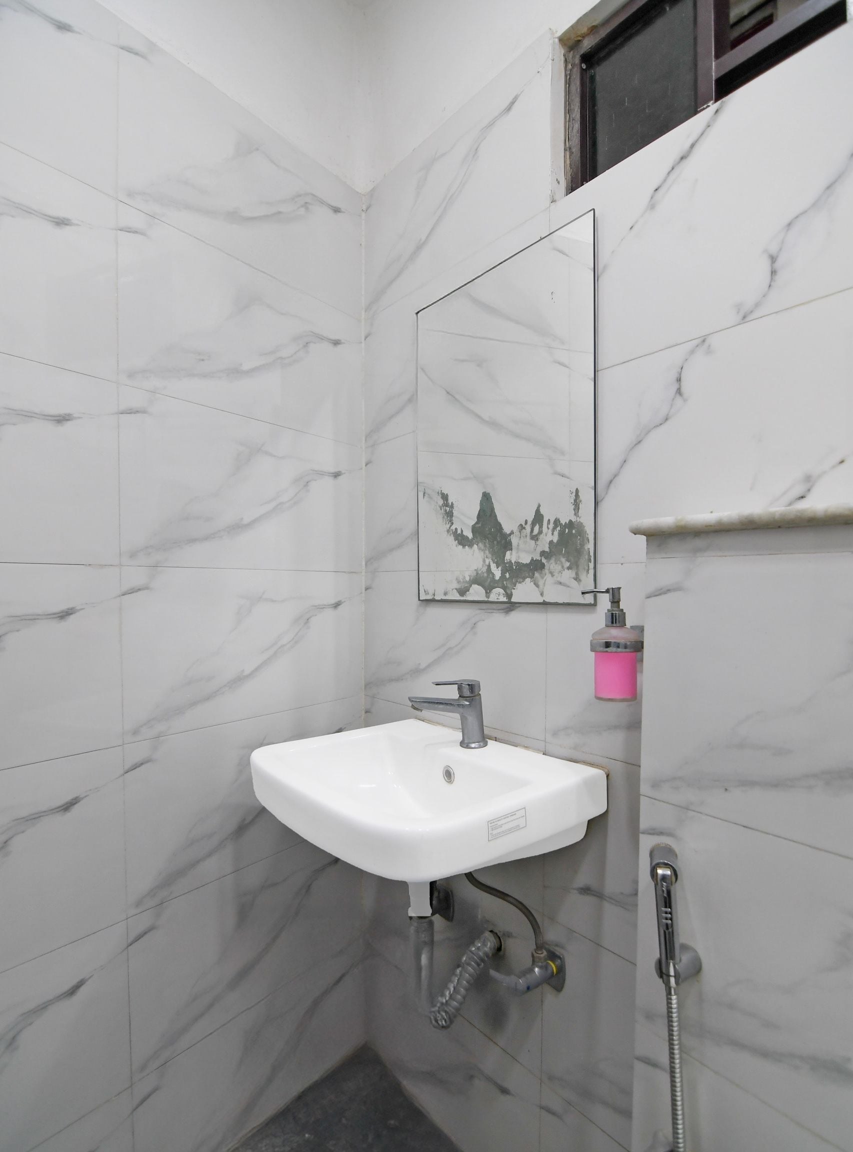 Un baño con lavamanos blanco, espejo y ducha.