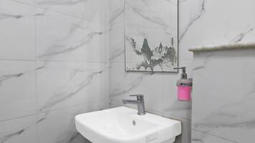 Un baño con lavamanos blanco, espejo y ducha.