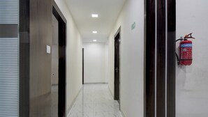A corridor with doors on both sides, a fire extinguisher mounted on the wall, and a ceiling light.
