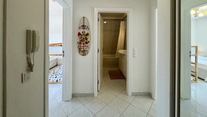 Käytävä, joka johtaa kylpyhuoneeseen, jossa on suihku ja wc.