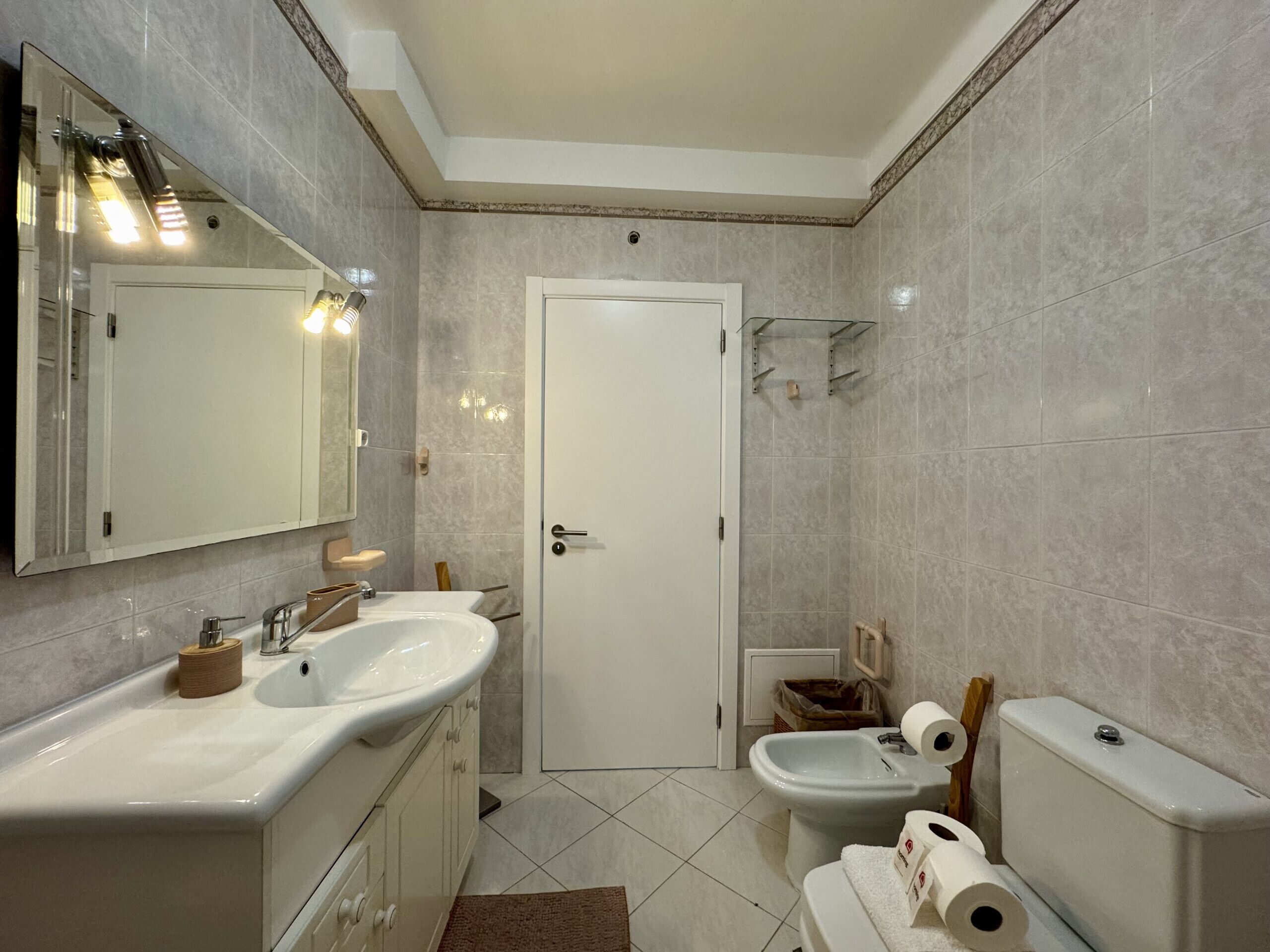 Un baño con lavamanos doble, inodoro, bidé y zona de ducha.