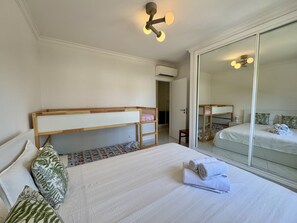 Een slaapkamer met stapelbedden, een grote spiegel en een plafondlamp.