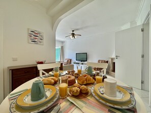 A dining area with a table set for breakfast, including croissants, muffins, and juice. - Vilamoura Golf Apartment 3 by Homing (Loulé)
