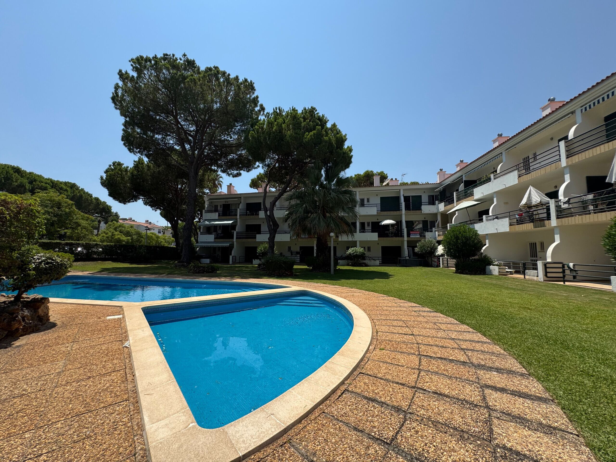 A swimming pool with a curved edge, surrounded by a pebble-tiled deck.