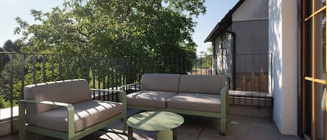 Un espacio al aire libre con sofá y sillones, una mesita y una barandilla.