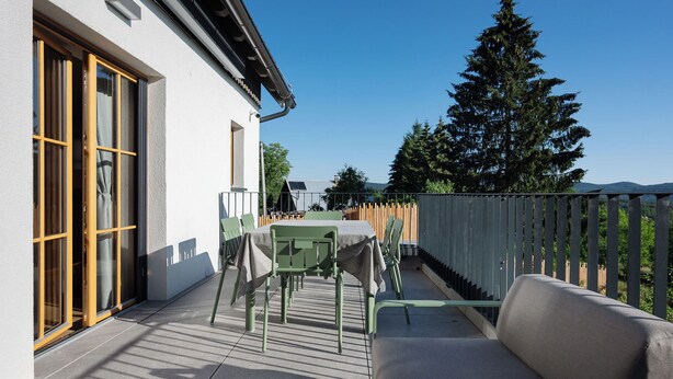 Eine Terrasse mit Tisch, Stühlen und einer Sitzecke, sowie ein Holzzaun.
