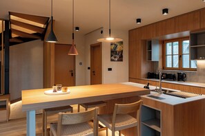 Eine moderne Küche mit einer Holzinsel, zwei Pendelleuchten und einem eingebauten Backofen.