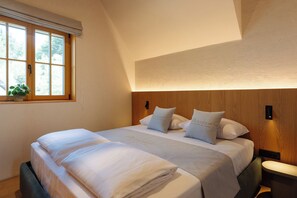 A double bed with a headboard, bedside tables, a window with a view, and a plant on the windowsill.