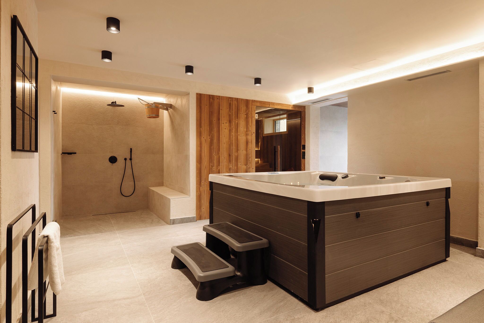 A modern bathroom with a large bathtub, a shower area, and a step leading to the shower.
