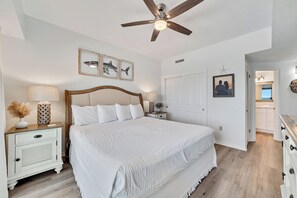 A bedroom with a large bed, a ceiling fan, and artwork on the wall. - Gulf front Bliss at The Palms 1015B - Orange Beach, AL - Signature Properties (Orange Beach)