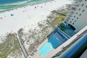 Une plage avec une piscine et un bâtiment doté de balcons.