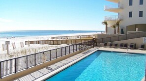 A pool area with a view of the beach, a wooden deck, and lounge chairs. - Gulf front Bliss at The Palms 1015B - Orange Beach, AL - Signature Properties (Orange Beach)