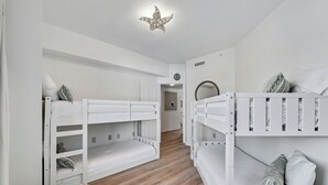 Habitació infantil amb llits superposats, un banc de vimetla i una làmpada de sostre amb forma d'estrella.