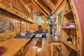 L’intérieur chaleureux d’un chalet avec des murs en bois, une cheminée, un canapé et une table à manger.