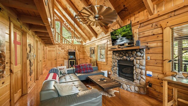 Ein Holzblockhaus-Interieur mit Kamin aus Stein, Ledersofa und einem Essbereich.