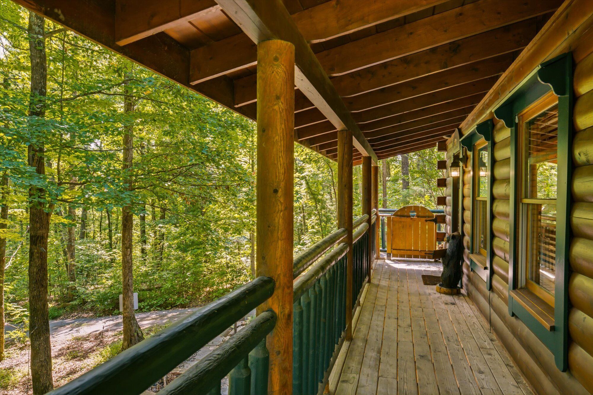 A wooden cabin with a covered porch, surrounded by a forest.