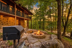 A stone building with a balcony, a fire pit, and a grill. - Marigold's Mountain Memories (Gatlinburg)