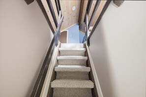Eine Treppe mit Teppichstufen und Metallgeländern, die zu einem Raum mit blauer Wand und Holzboden führt.