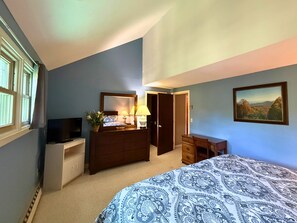 Une chambre à coucher avec un lit, une commode, un bureau et un tableau accroché au mur.