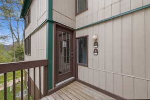 A building with a wooden deck, a brown door with a window, and a parking meter on the wall. - Three Bedroom condo- 200 yard walk to ski slopes (Sugar Mountain)