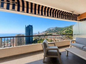 Un balcon donnant sur un paysage urbain, une chaise, une table et un canapé.
