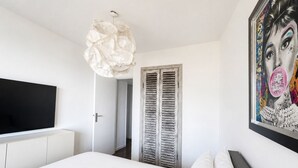 Une chambre à coucher avec un lit, une télévision, une porte et un mur orné d’un tableau.