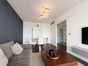 Un salon moderne comprenant un canapé, une table basse et un coin repas avec des chaises et une table.