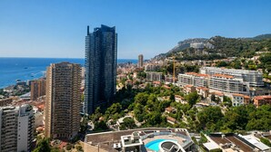 Un paysage urbain côtier avec des immeubles modernes de grande hauteur, un ciel bleu dégagé et une vue sur la mer.