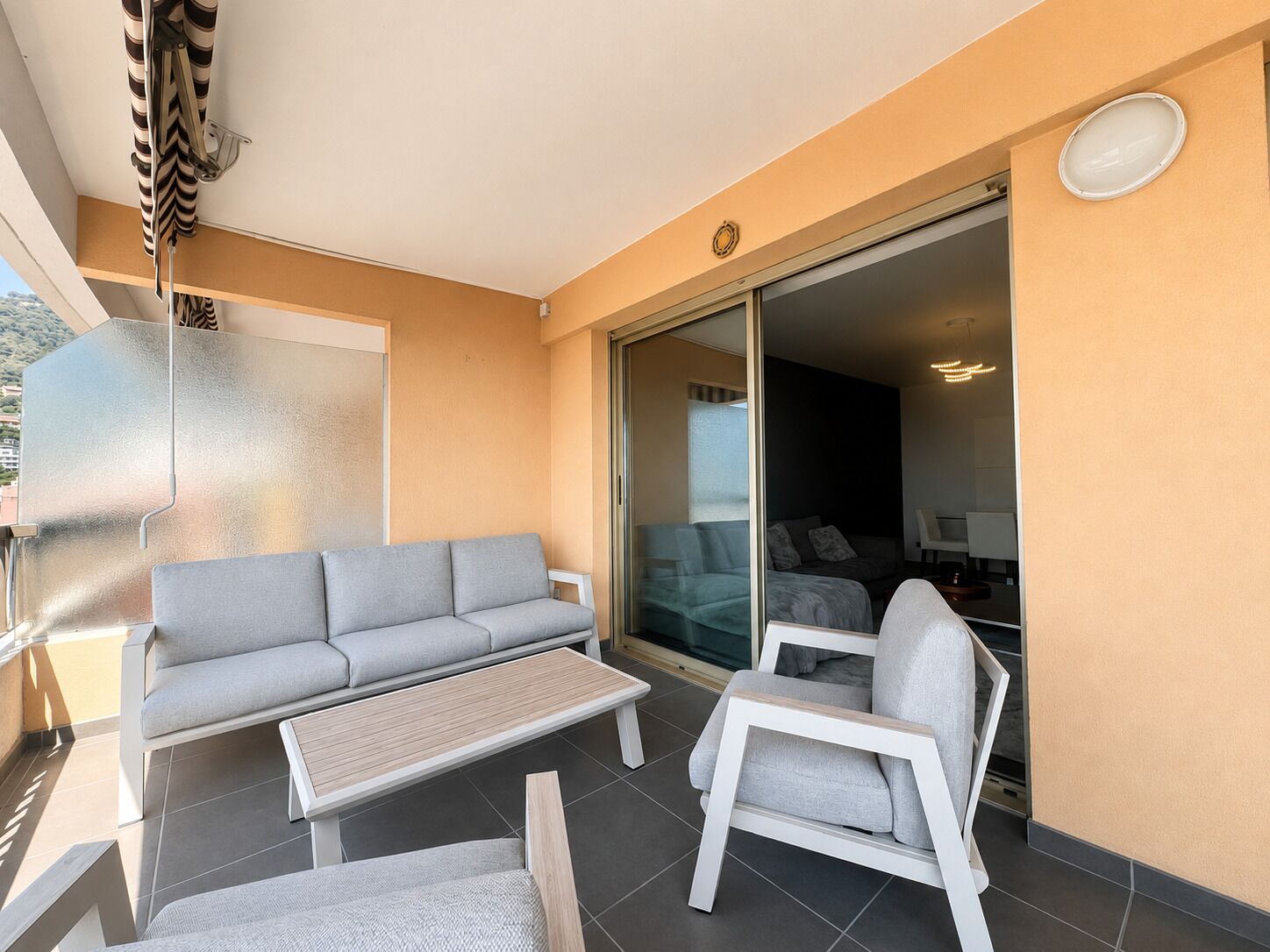 A balcony with a sofa, a chair, and a table.