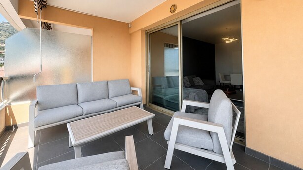Un balcon avec un canapé, une chaise et une table.