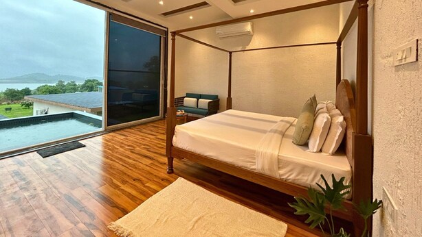 Een moderne slaapkamer met een hemelbed, uitzicht op een zwembad en een plafondventilator.