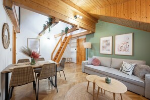 A spacious living area with a wooden ceiling, a dining table with chairs, a sofa, and a staircase. - Luxury 2BR Apartment Steps from Old Town Square (Praha)