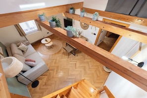 A loft-style living space with a herringbone wood floor, a sofa with cushions, a round coffee table, and a dining area with a small table and chairs. - Luxury 2BR Apartment Steps from Old Town Square (Praha)