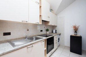 A kitchen with white cabinets, a double sink, a dishwasher, and a black refrigerator. - Luxury 2BR Apartment Steps from Old Town Square (Praha)