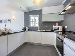 A modern kitchen with white cabinets, a built-in microwave, and a stainless steel range hood. - Villa Louisa - Garden Villa, Carvoeiro (Carvoeiro)