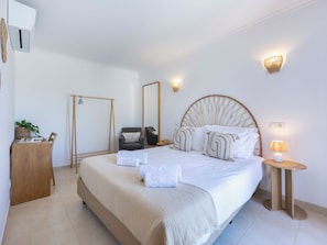 Ein modernes Schlafzimmer mit einem großen Bett, Nachttischen, einem Kleiderschrank und einem Spiegel.