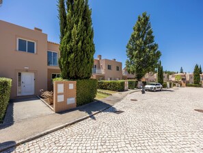 A residential street with cobblestone pavement, modern two-story houses, and a parked car. - Villa Louisa - Garden Villa, Carvoeiro (Carvoeiro)