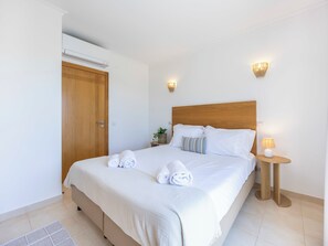 A hotel room with a large bed, a wooden headboard, two bedside tables with lamps, and a wooden wardrobe. - Villa Louisa - Garden Villa, Carvoeiro (Carvoeiro)