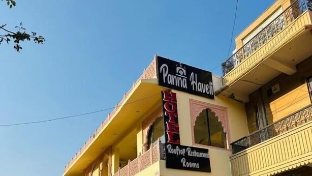 A two-story building with a sign for 'Panna House Rooftop Restaurant' and 'Rooms.'